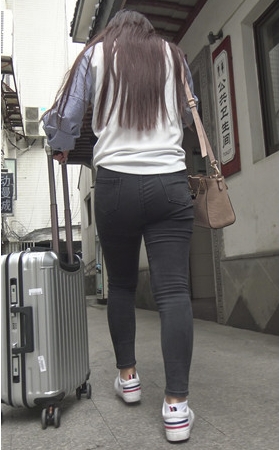 推着行李箱的黑色紧身牛仔裤女孩
