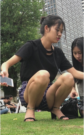 草地上玩手机的漂亮小姐姐