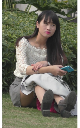 草地上玩手机的美女