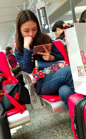 高铁站候车的蓝色紧身牛仔裤长发美少妇