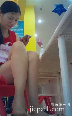 边玩手机边挑些等孩子玩蹦蹦床的红衣少f