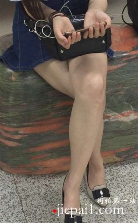 尖嘴高跟齐逼牛仔短裙妹子坐在玉石上看手机视频。